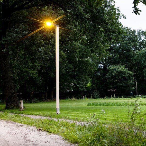 Houten lantaarnpaal langs de weg en het fietspad op grasvlakte