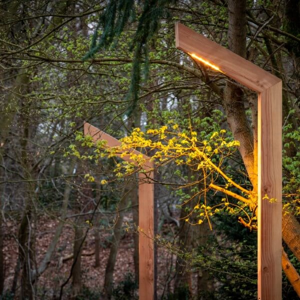 Houten lantaarnpaal met uithouder in een hoek in het bos